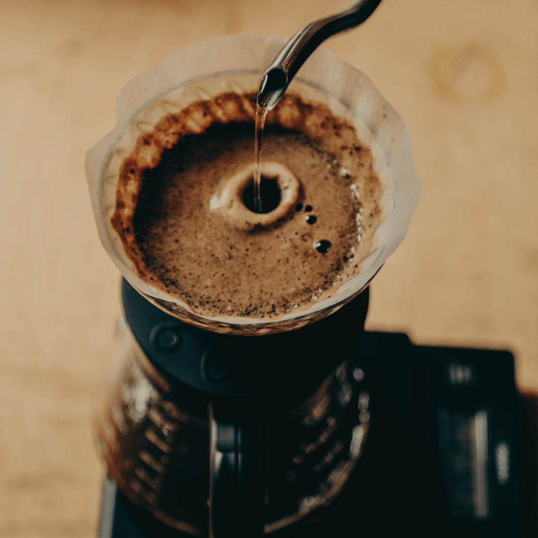 En dampende kop filterkaffe lavet med lysristede kaffebønner, kendt for deres høje indhold af antioxidanter, præsenteret på et bord med naturlige omgivelser – den perfekte sunde kaffeoplevelse.