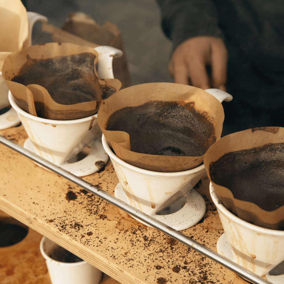 En kop friskbrygget kaffe på et træbord, omgivet af kaffebønner – perfekt til at illustrere emnet om koffeinens fordele og ulemper.