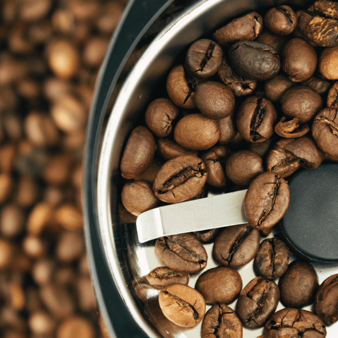 En kop friskbrygget kaffe ved siden af hele kaffebønner og formalet kaffe – en visuel sammenligning af forskellen mellem de to typer.