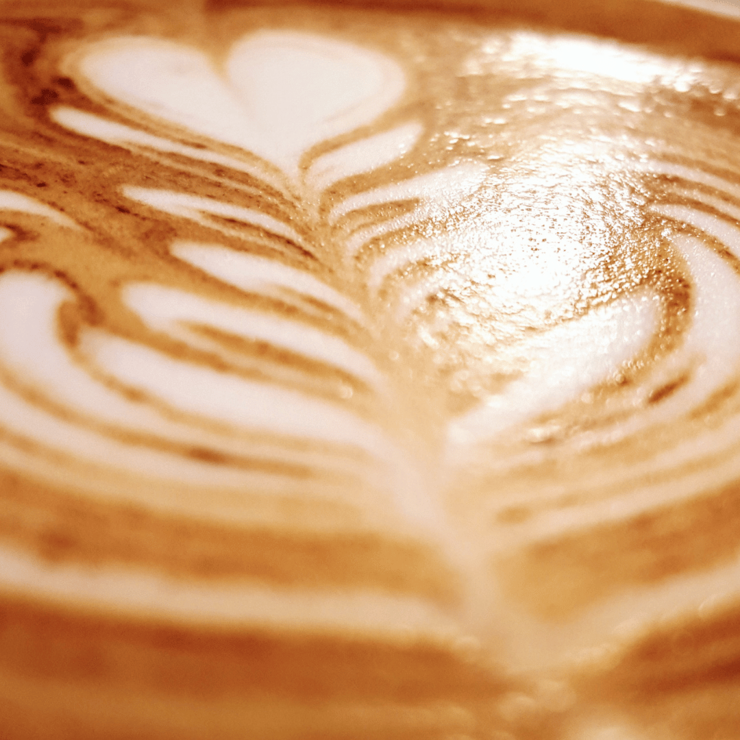 En kop kaffe med smukt latte art mønster, lavet af steamet mælk i en espresso. Perfekt eksempel på latte art for begyndere, hvor simple mønstre som hjerter og rosetter kan laves med den rette teknik og øvelse.
