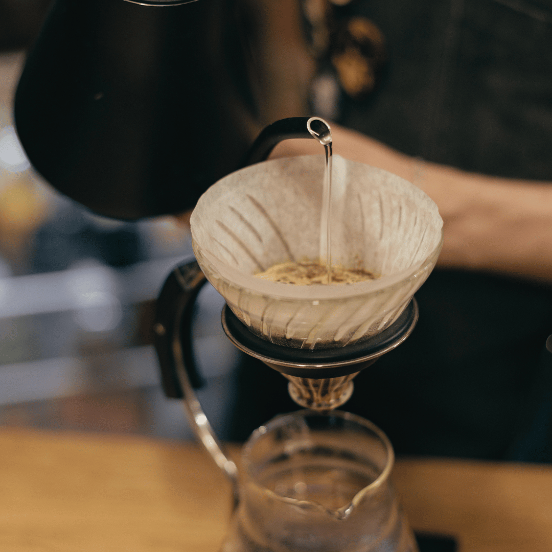 Et glas filtreret vand og en dampende kop kaffe, der fremhæver kaffens smagsnuancer og sikrer en optimal kaffeoplevelse.