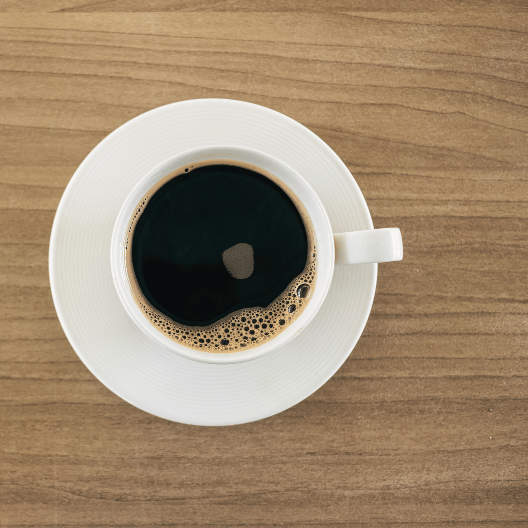 Et glas med kaffebønner ved siden af en kaffekop, der illustrerer spørgsmålet: Kan man stadig bruge kaffe efter udløbsdatoen?