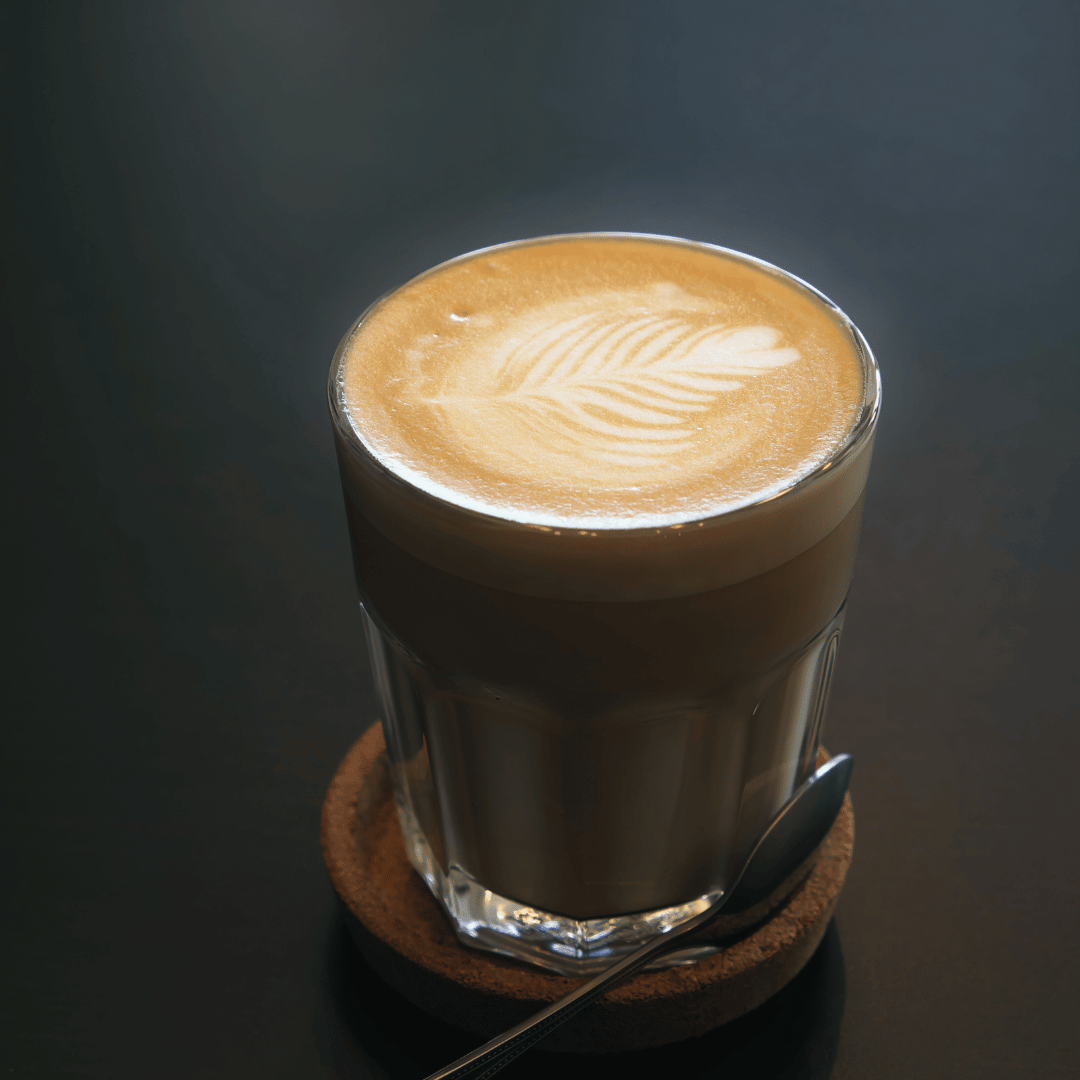 En perfekt brygget flat white serveret i en kaffekop, med et glat lag mikro-skum på toppen. Denne kaffedrik er lavet med en dobbelt espresso og dampet mælk, der giver en rig og cremet kaffeoplevelse.