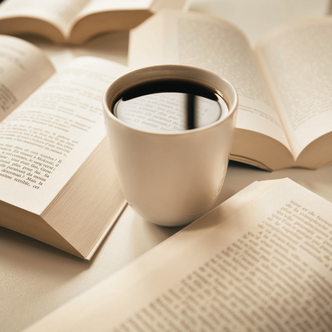 En person drikker kaffe om morgenen ved et bord med en bog, hvilket symboliserer, hvordan korrekt kaffeforbrug kan forbedre både produktivitet og søvnkvalitet.