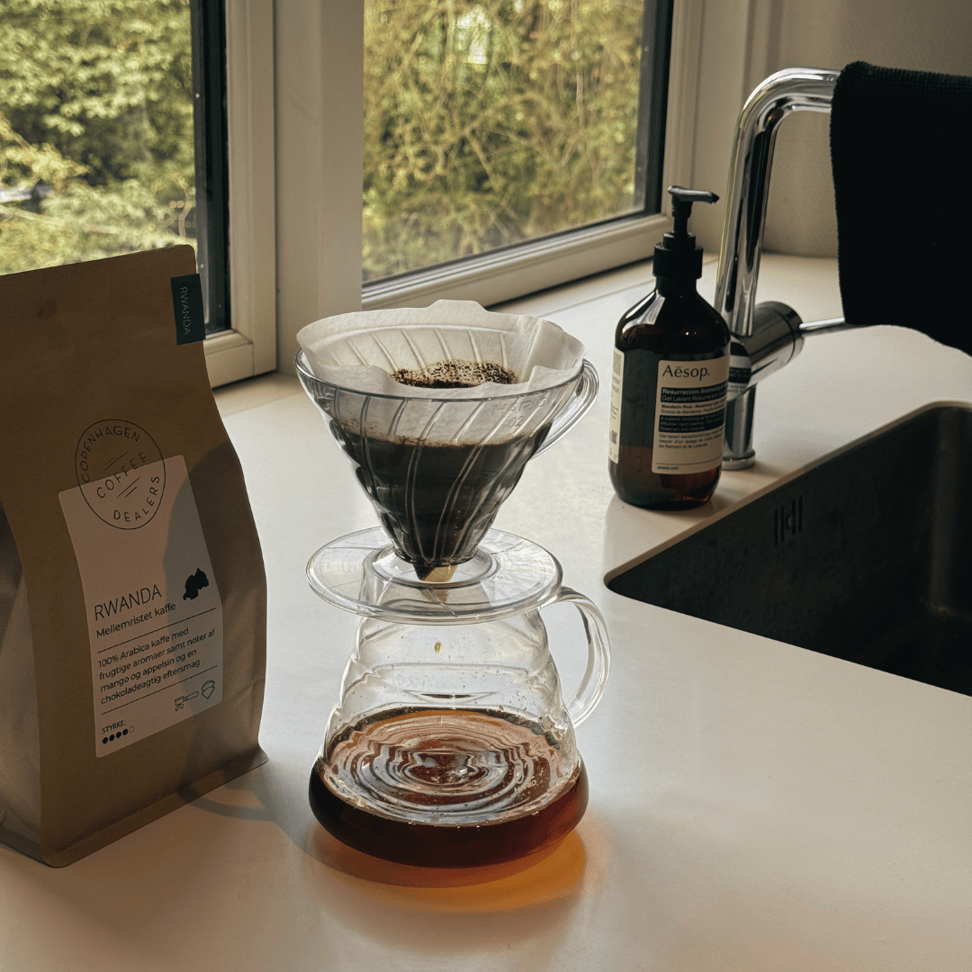 En pour-over kaffebrygger med blooming-fasen i gang, hvor kaffegrumset svulmer op og frigiver CO2 for en optimal ekstraktion.