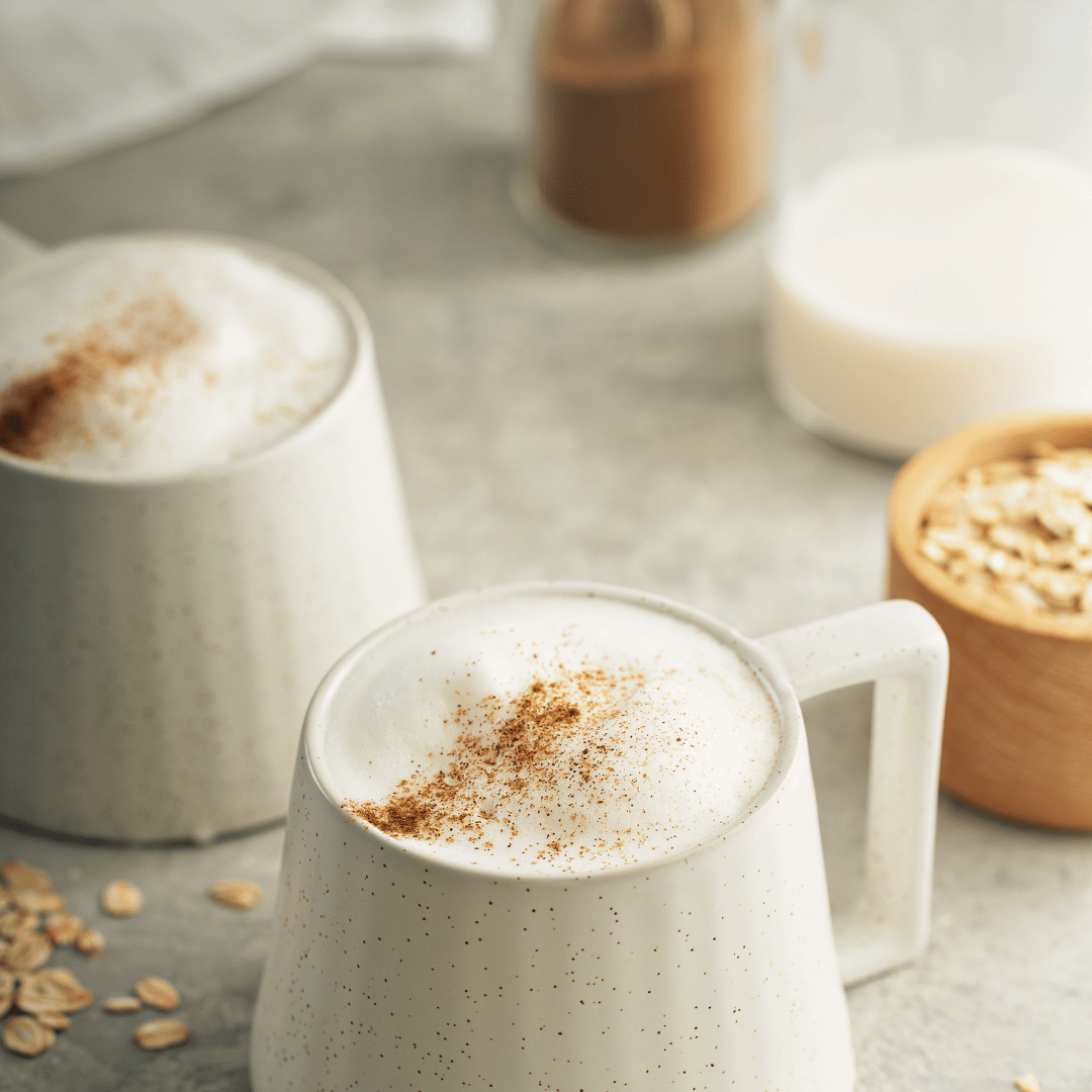 En sund latte lavet med cremet havremælk, toppet med et drys kanel og serveret i en elegant kop. Perfekt for kaffeelskere, der søger en laktosefri og bæredygtig kaffeoplevelse.