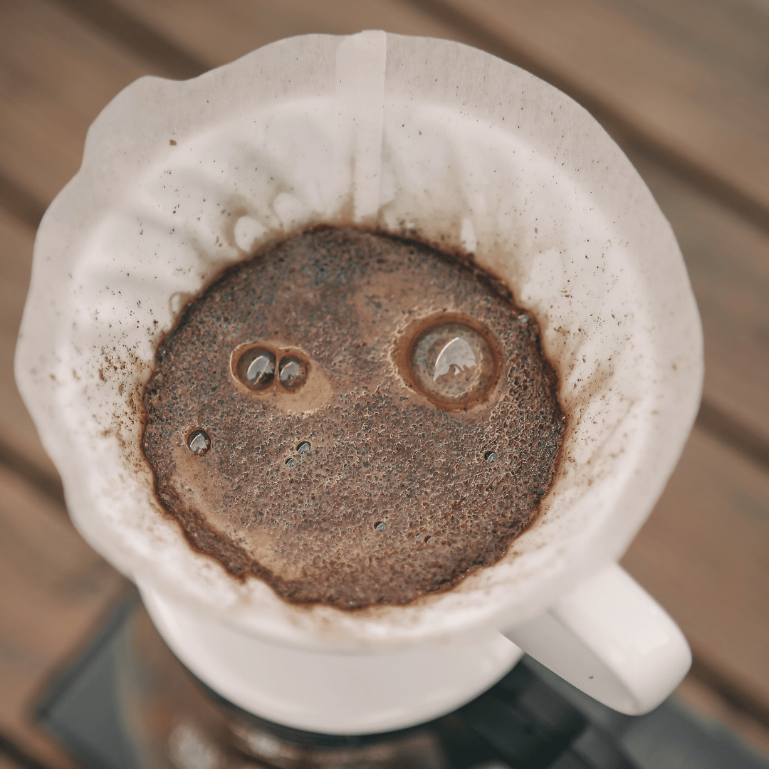 En kop kaffe ved siden af forskellige bryggeudstyr, der illustrerer kaffebrygningens udvikling fra traditionelle metoder til moderne teknikker.