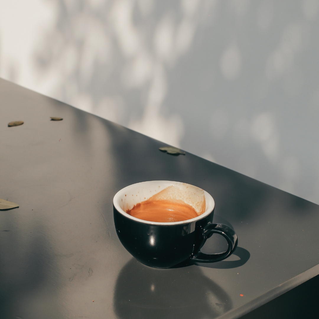 Kaffekop ved siden af en gravid kvinde, der repræsenterer sikker koffeinindtag under graviditet på maksimalt 200 mg dagligt, svarende til 1 kop filterkaffe eller 2 små kopper espresso.